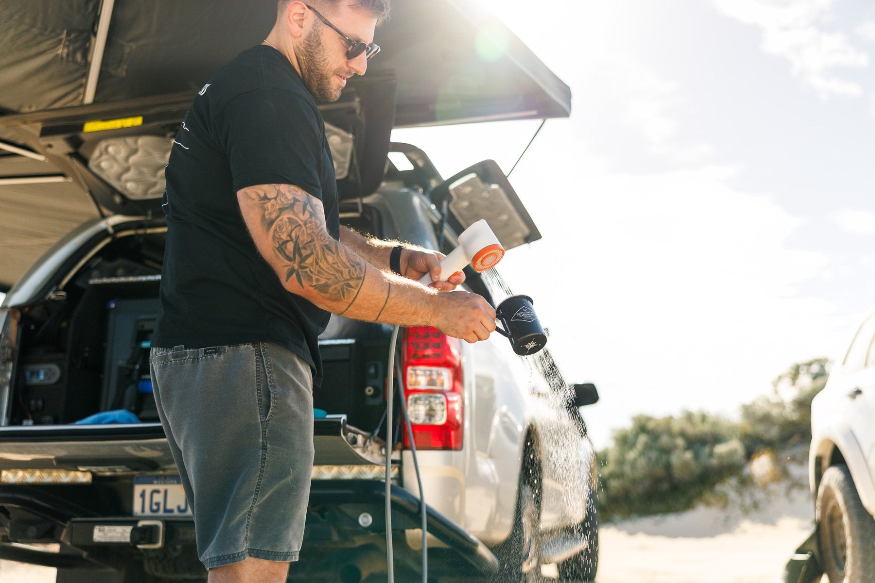 Portable rechargeable camping shower set up beside a 4WD at an Australian campsite