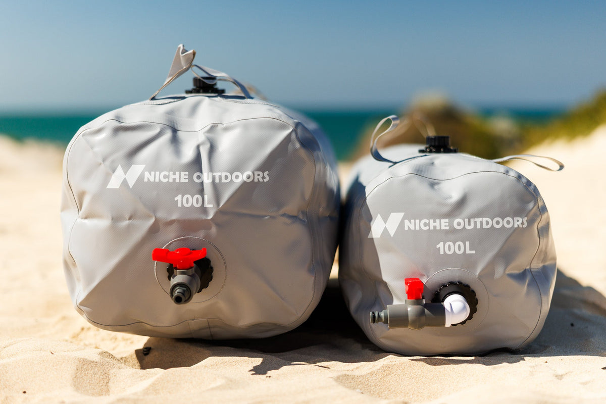 Niche Outdoors 100L Slim and Wide water bladders side by side on a beach